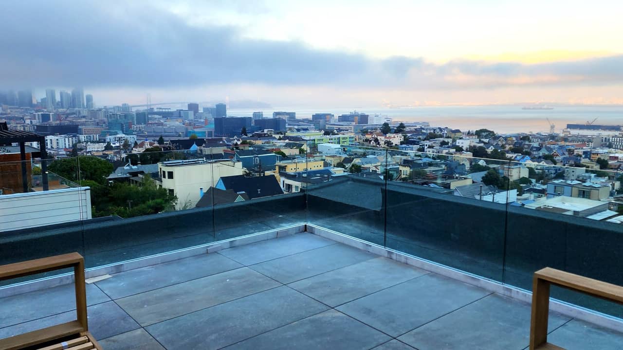 Frameless glass rooftop guardrail overlooking San Francisco at dawn