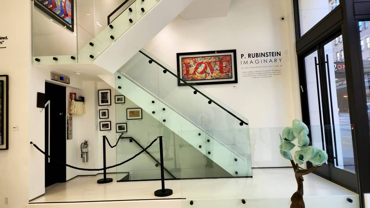 Glass stair balustrade with steel standoffs in a two-story art gallery