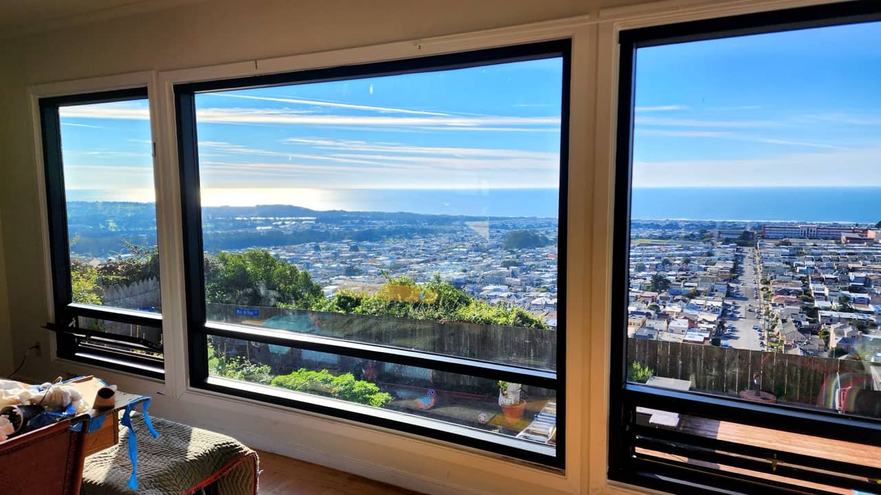 Wide picture windows framing an ocean and rooftop view across San Francisco
